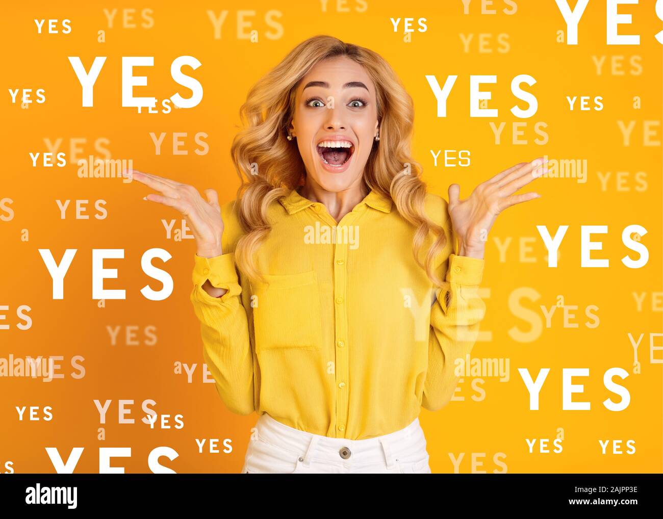 Surprise reaction. Excited screaming young girl jumping with raised hands over yellow background
