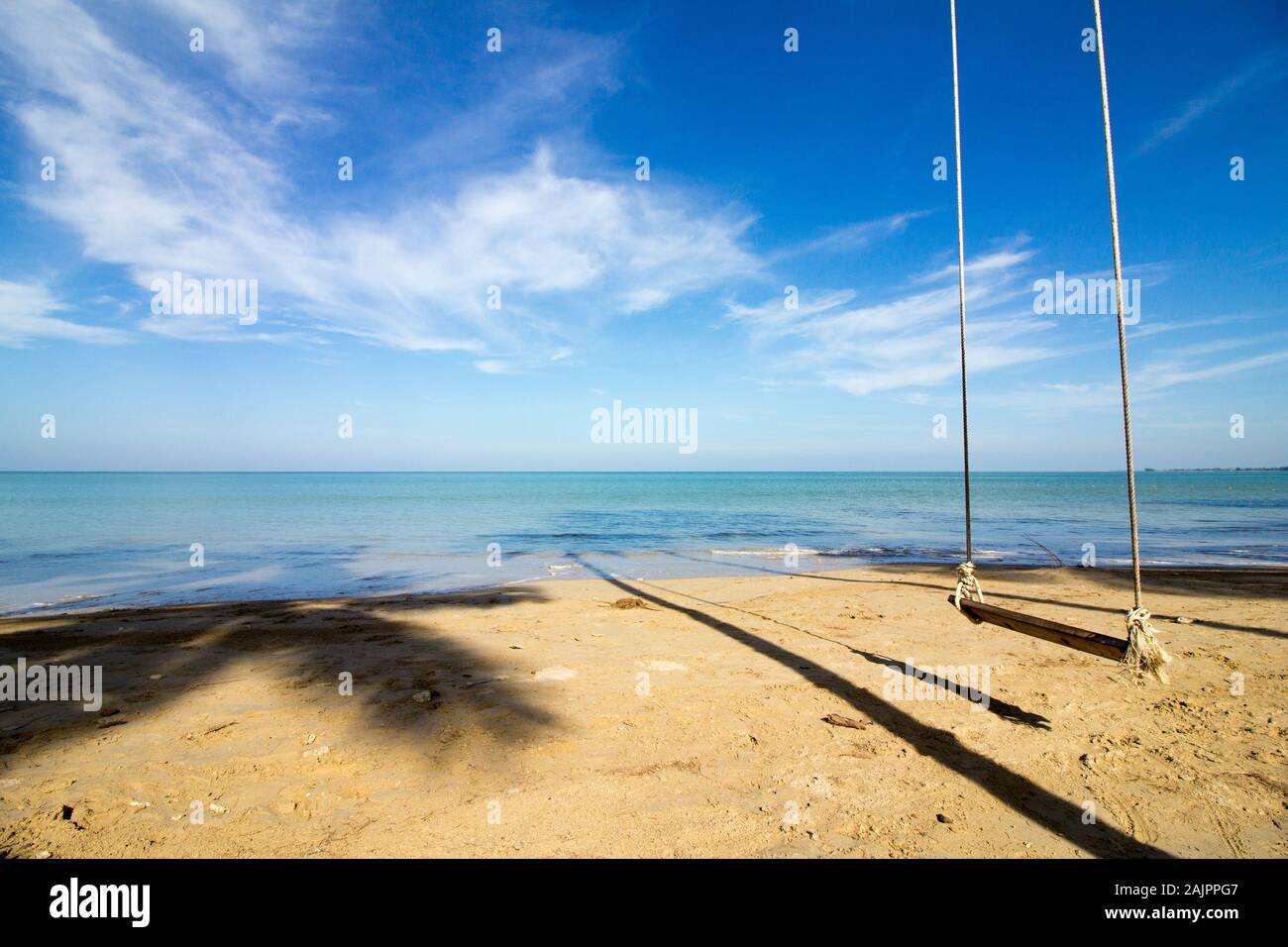 lonely swing on a dreamlike beach in front of a heavenly turquoise sea Stock Photo