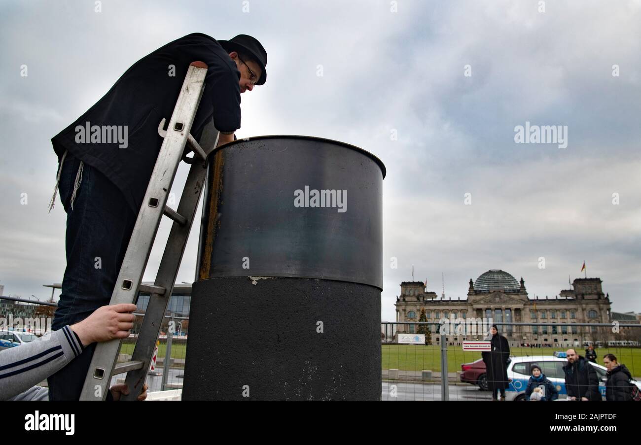 Berlin, Germany. 05th Jan, 2020. 05 January 2020, Berlin: The author Eliyah Havemann reattaches a previously dismantled steel plate to the controversial steel column of the artists' collective 'Centre for Political Beauty' (ZPS) opposite the Reichstag building. Several activists have tried to dismantle the controversial steel column of the artists' collective 'Centre for Political Beauty' (ZPS) in Berlin. 'One should not make art and politics with ashes of victims of the Holocaust,' Havemann told the dpa on Sunday, explaining the reasons. The police stopped the action and ZPS filed a complaint Stock Photo