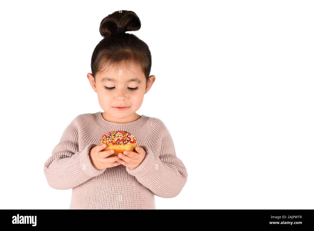 Happy little cute child eating donut with bright candies on isolated white background. Stock Photo