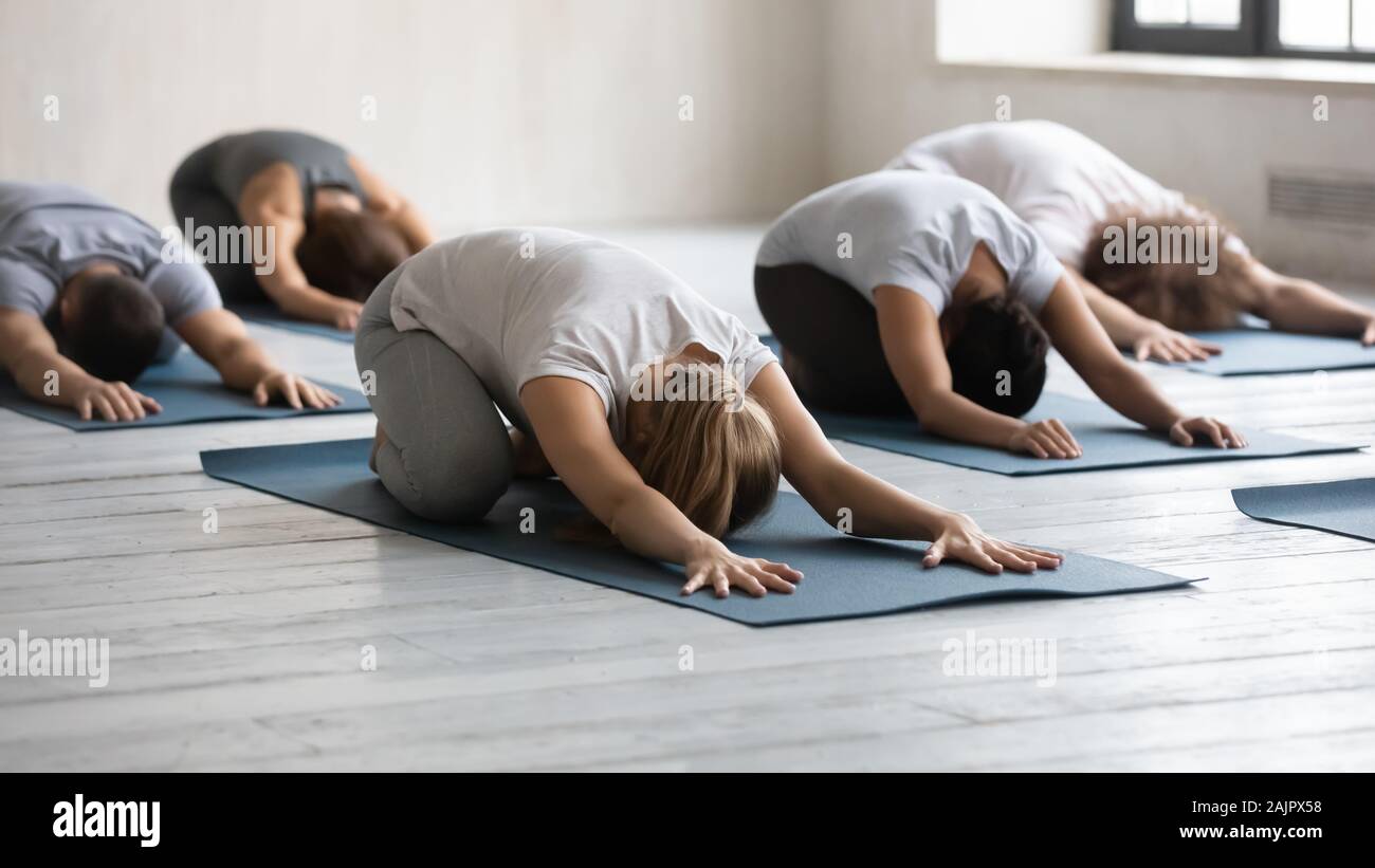 Diverse people doing child exercise at group lesson, practicing yoga Stock Photo