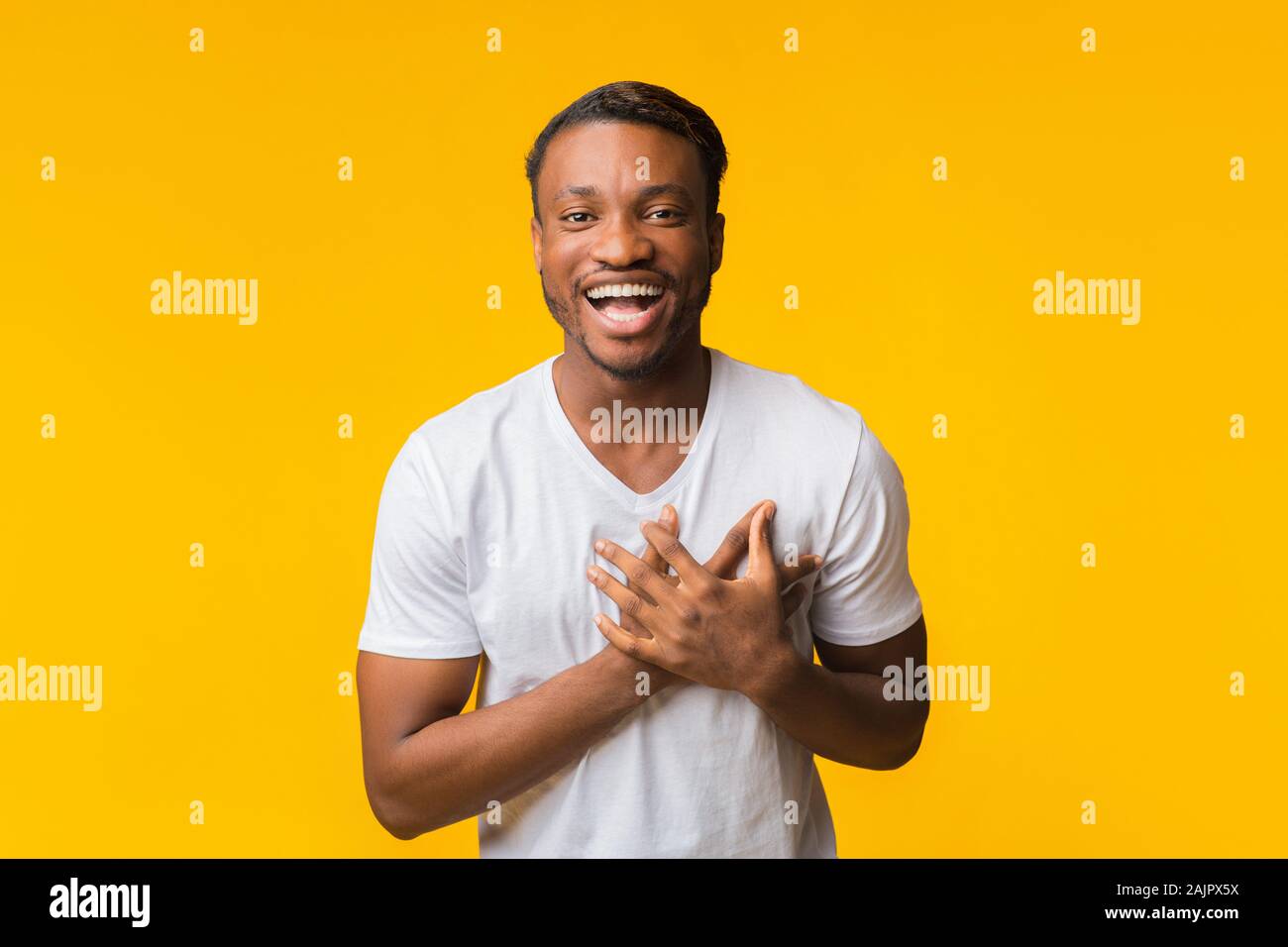 Positive African American Man Laughing All Heartedly Touching Chest Looking At Camera Standing Over Yellow Background. Studio Shot Stock Photo