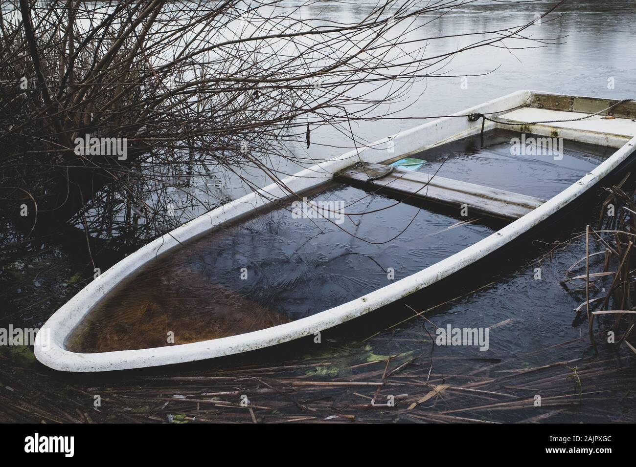 a sunken rowing boat lies on the shore of a frozen small lake Stock ...