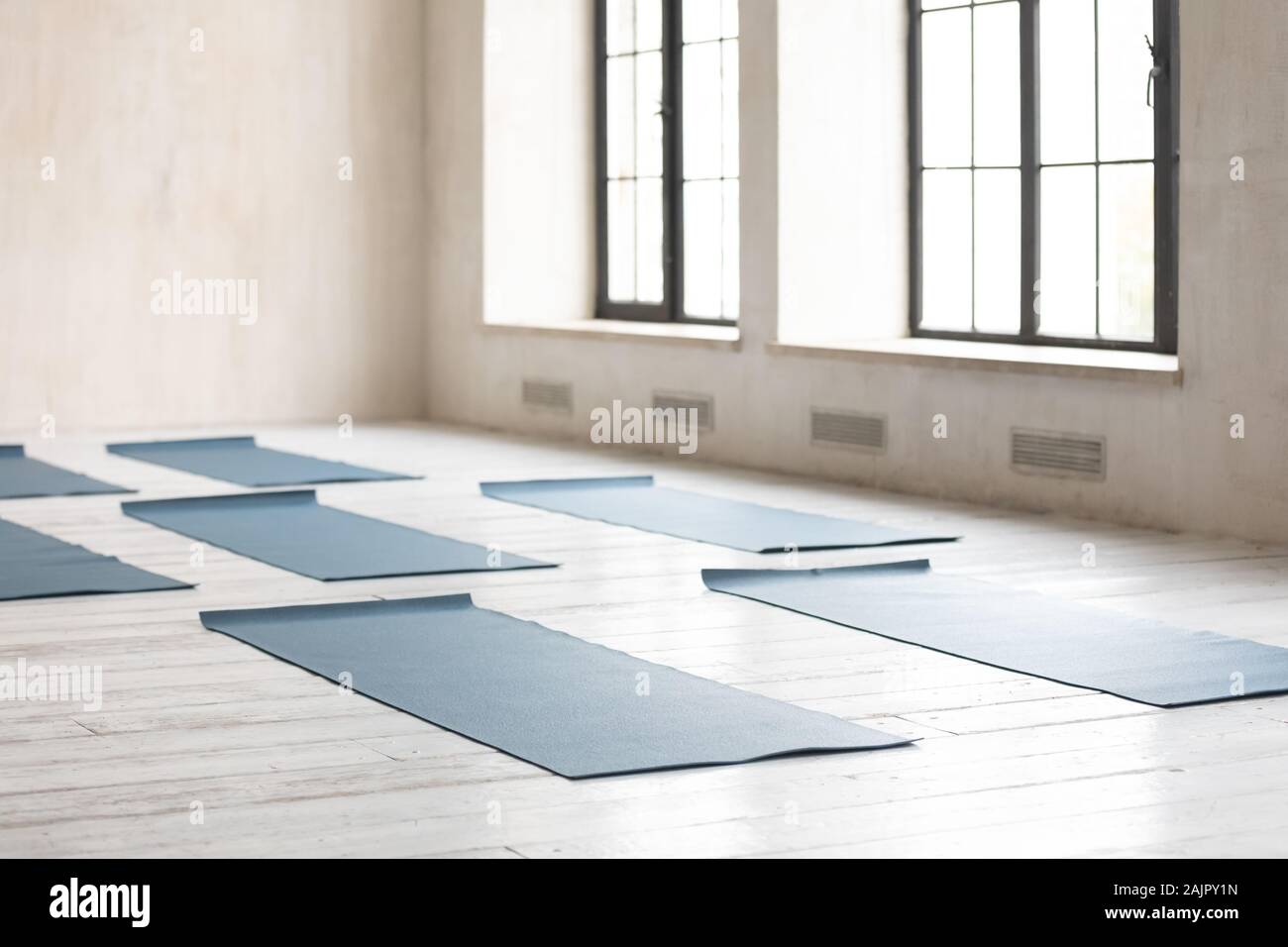Unrolled yoga mats on wooden floor in empty fitness center Stock