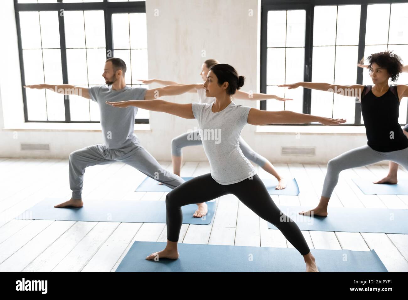 Diverse young people practicing yoga, doing Warrior two exercise Stock Photo