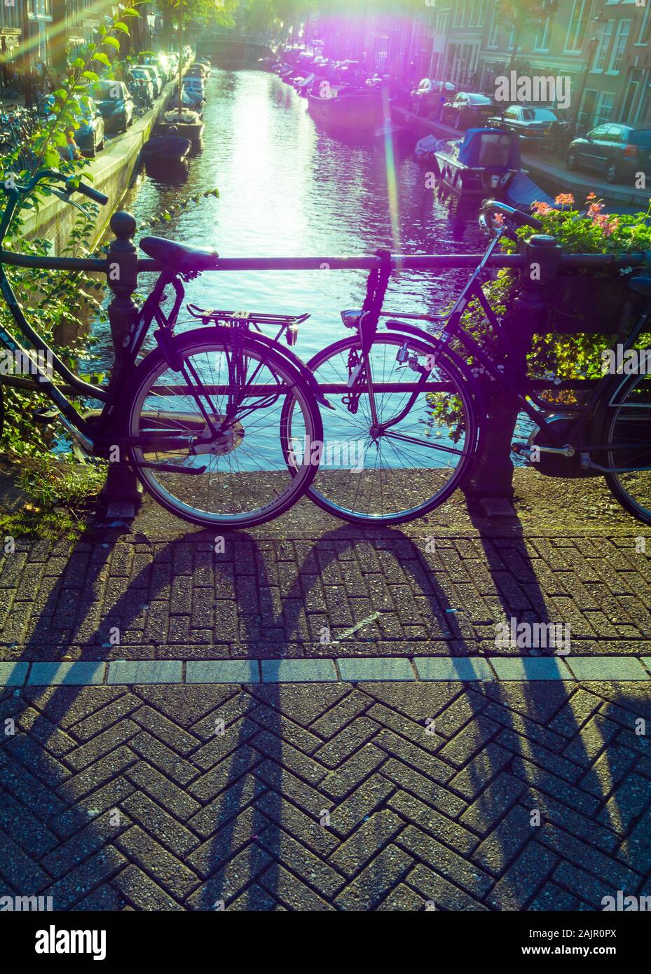 Off-color image of parked bicycles on a canal bridge in Amsterdam's old Jordaan quarter (Egelantiersgracht). Vintage polaroid color style, lens flare. Stock Photo