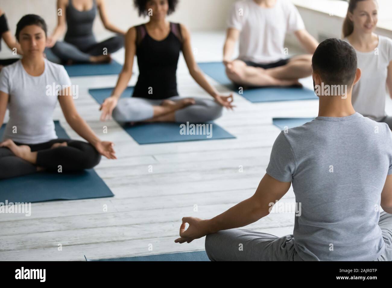 Trainer teaching diverse people practicing yoga, doing Padmasana exercise Stock Photo