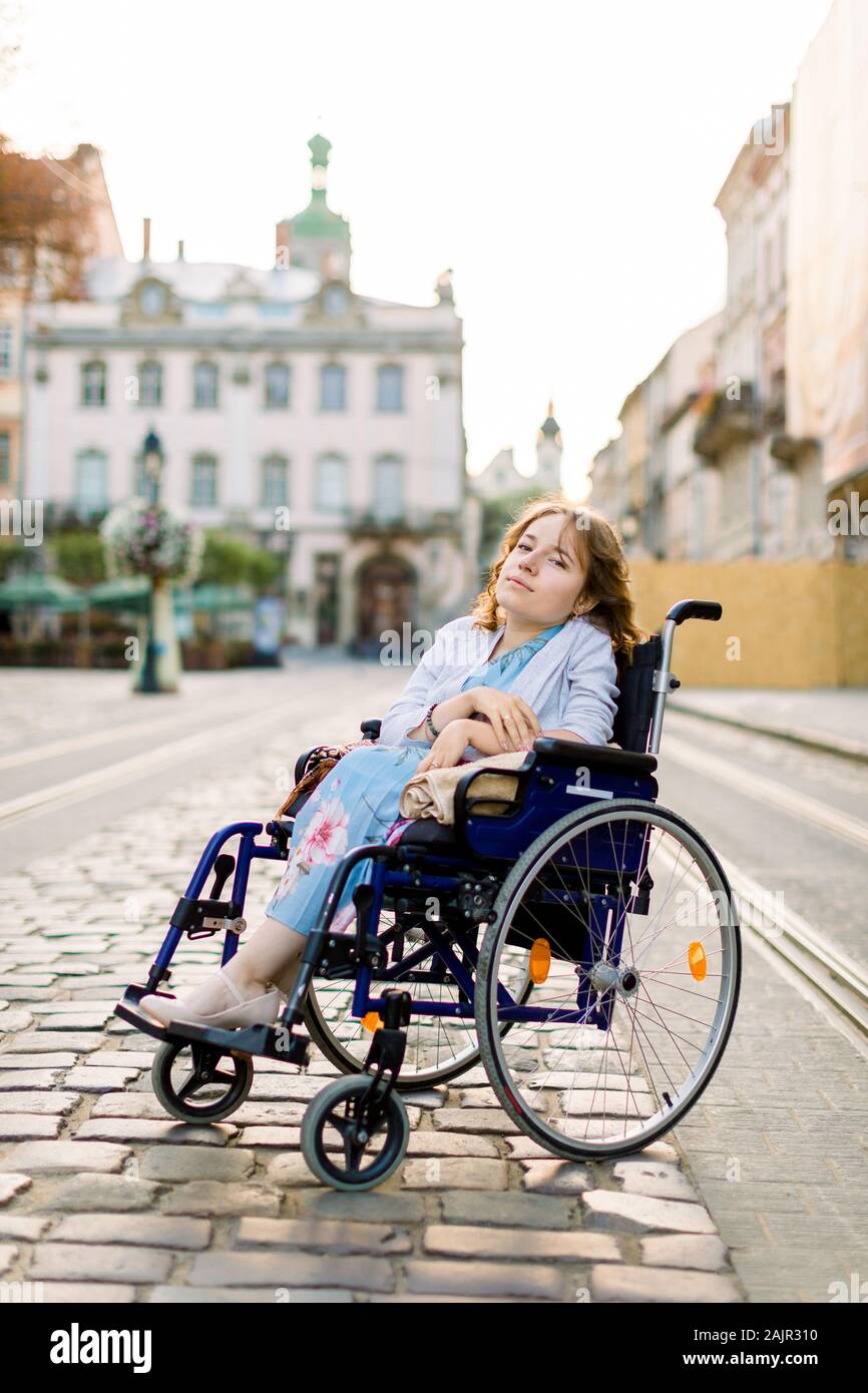 A girl in blue dress in a wheelchair outdoors in the city. The disabled  person enjoys life. Young beautiful disabled woman Stock Photo - Alamy