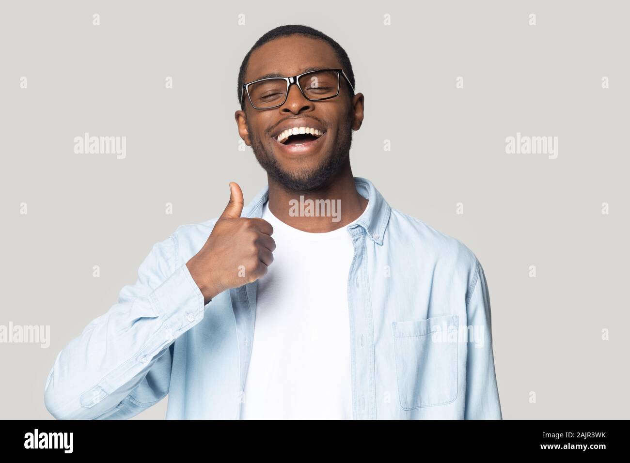 African guy showing thumbs up looking at camera studio shot Stock Photo