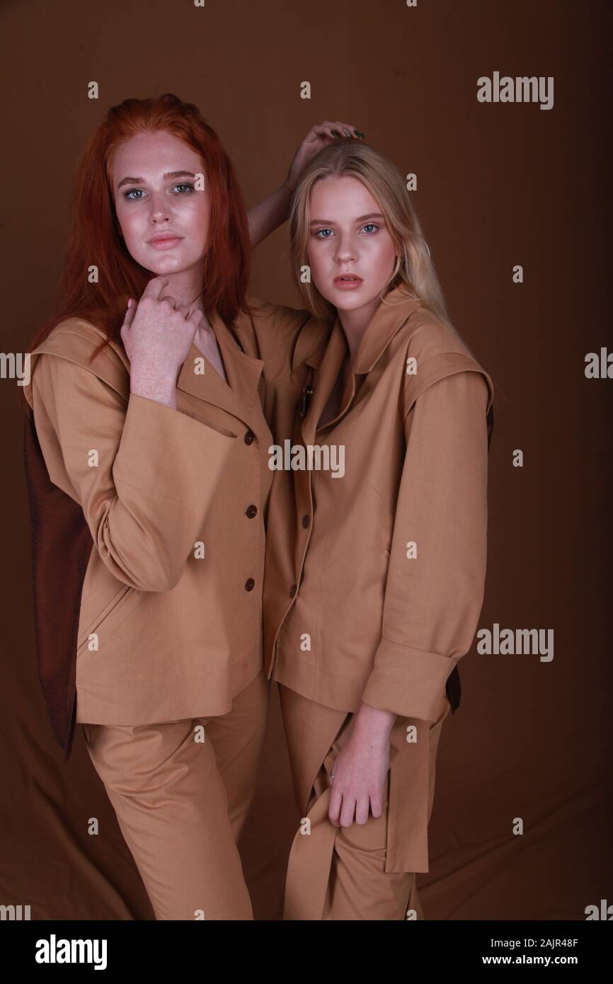Two beautiful girls blond and ginger hair wear same style and color  clothing for every day, summer spring collection suit made cotton beige  color Stock Photo - Alamy
