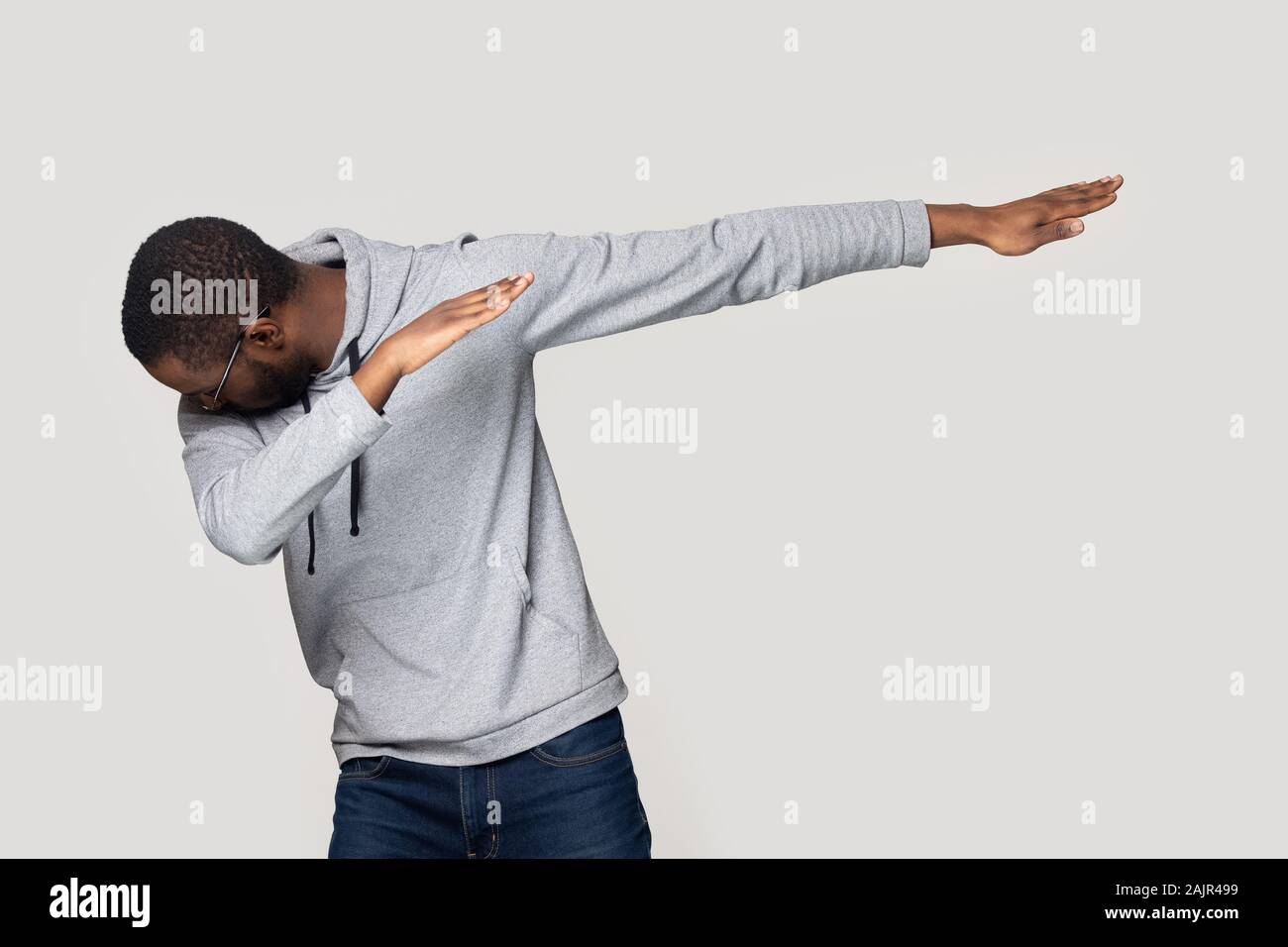 African guy performing dabbing dance isolated on grey studio background Stock Photo