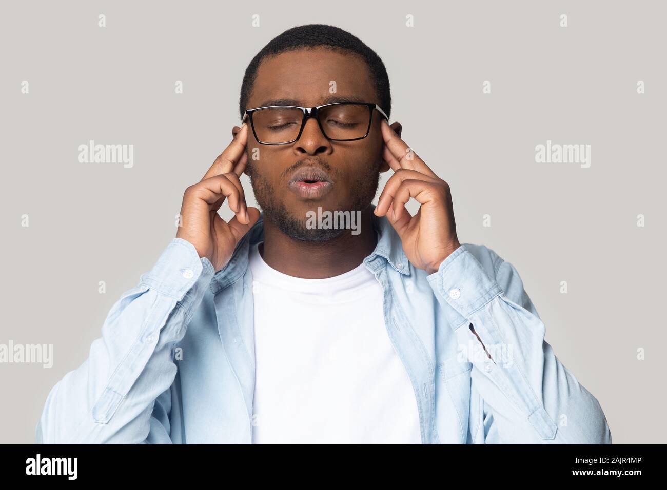 African guy closed eyes touches temples inhales exhales studio shot Stock Photo