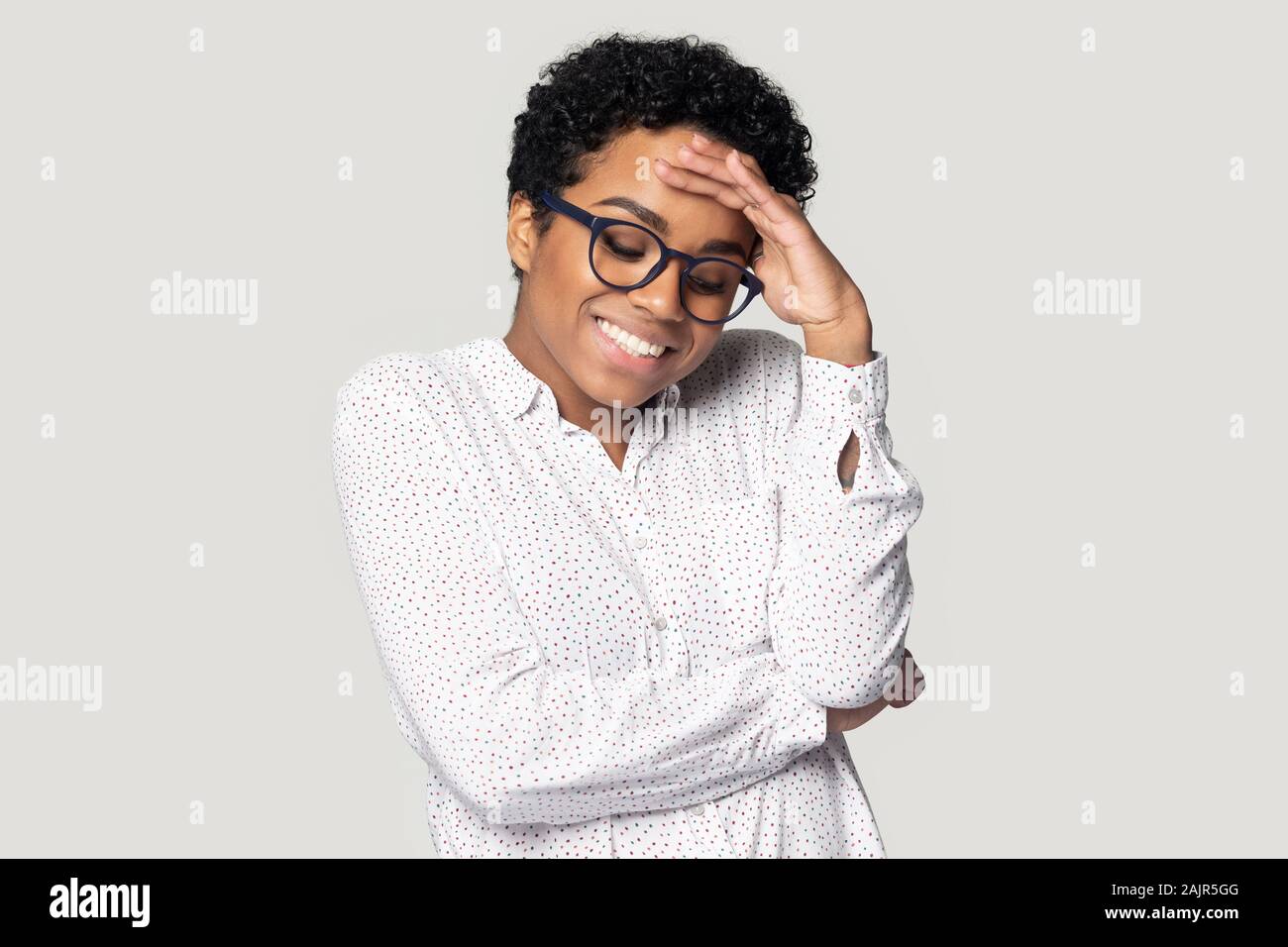 African woman lowers eyes down and looks embarrassed studio shot Stock Photo