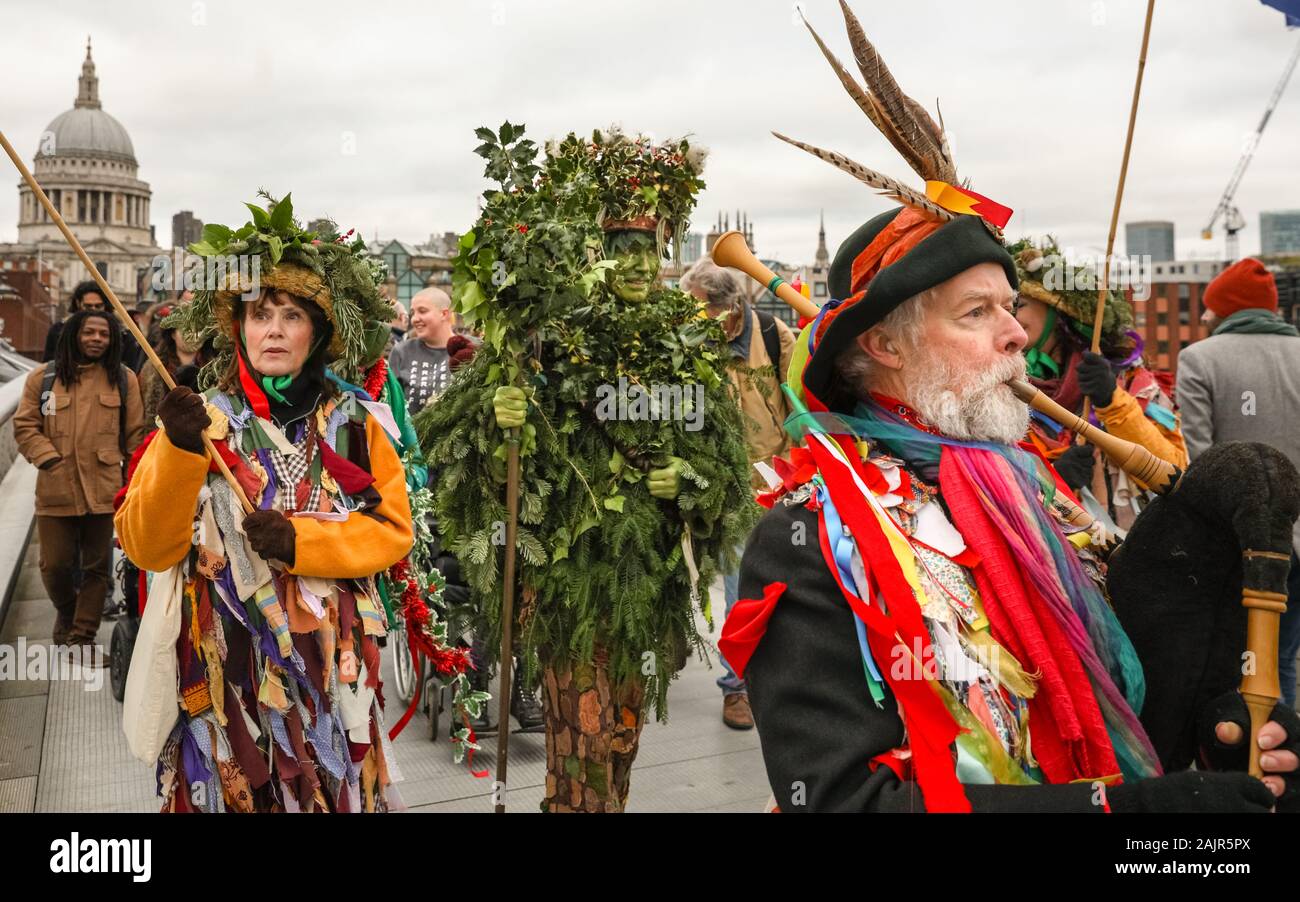 London, UK. 5th Jan 2020. The Holly Man on the Millennium Bridge. The 25th annual Twelfth Night Celebration, an ancient Midwinter custom, is held at Bankside, performed by 'The Lions part' players. The Holly Man, decked in green foliage, is piped over the River Thames. He is joined by the London Mummers, to toast (wassail) the people, and perform freestyle folk combat play in colourful costumes. The procession moves across the river, to Shakespeare's Globe and on to the St George Inn, Southwark. Credit: Imageplotter/Alamy Live News Stock Photo