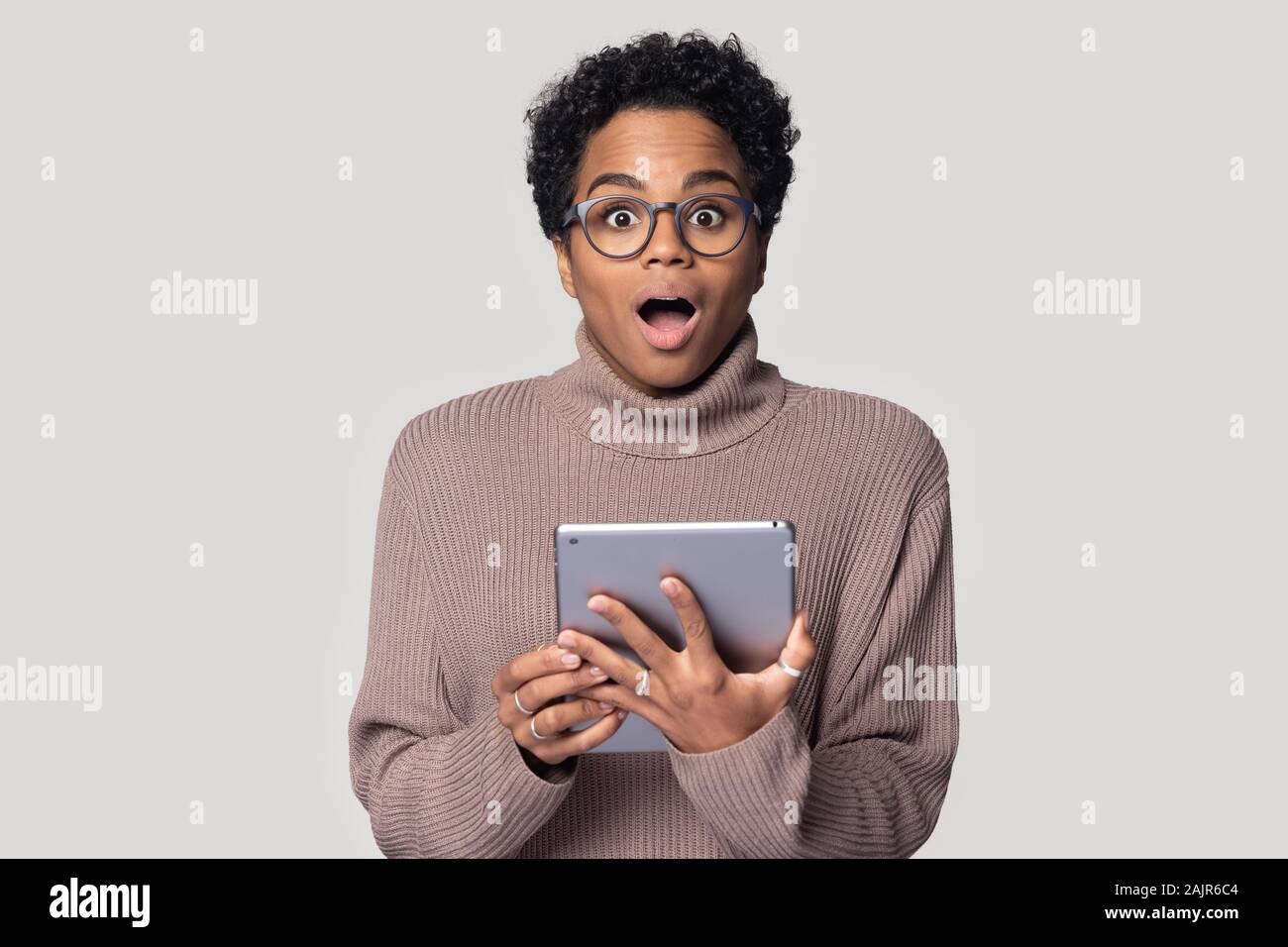 Amazed african woman holding tablet read breaking news, studio shot Stock Photo