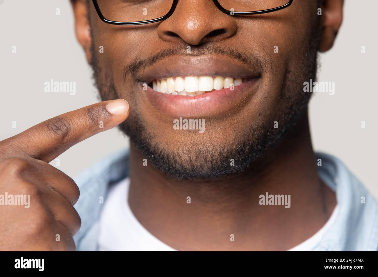 Closeup view african guy pointing finger to white toothy smile Stock Photo
