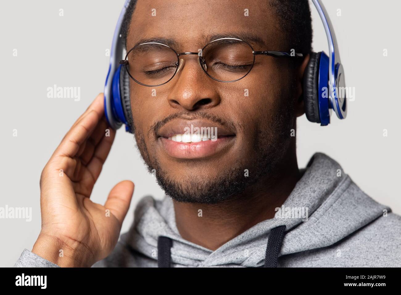 African guy using blue headphones listen music studio shot Stock Photo
