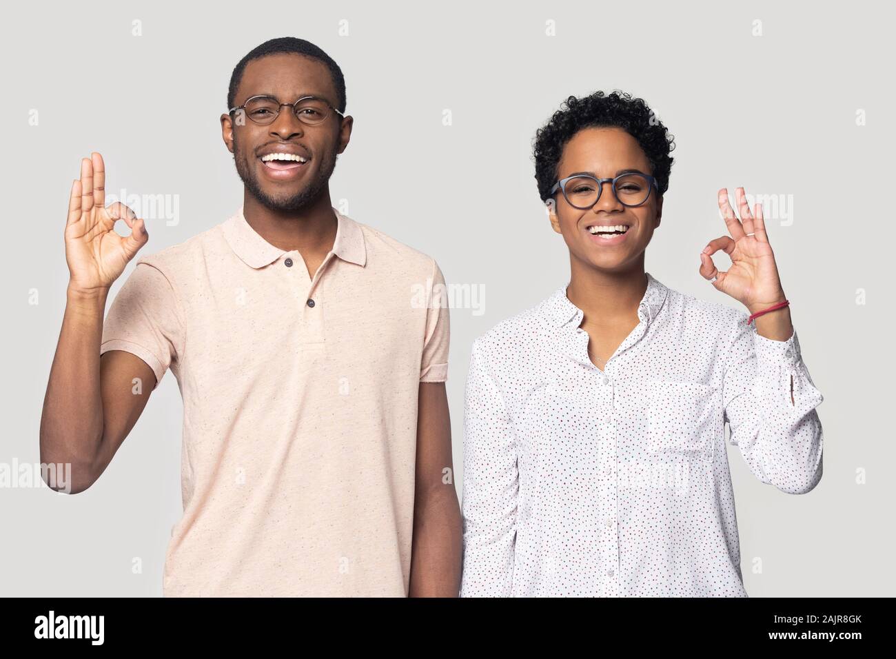 Happy african couple look at camera showing ok hand gesture Stock Photo
