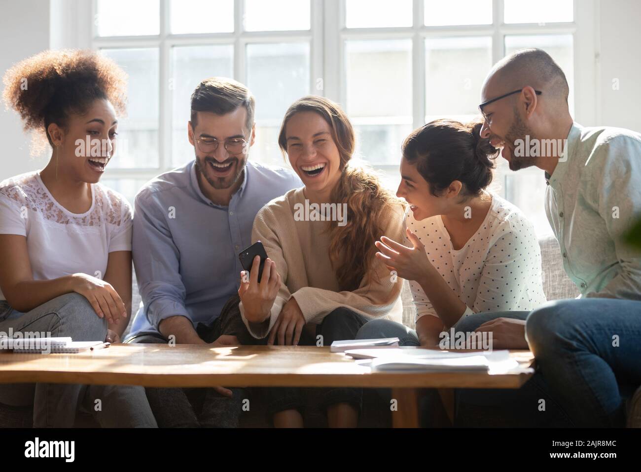 Overjoyed young people have fun using cellphone together Stock Photo