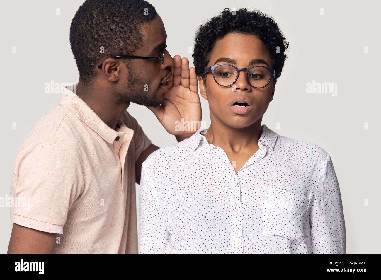 African guy whispering to ear of girl secret, studio shot Stock Photo