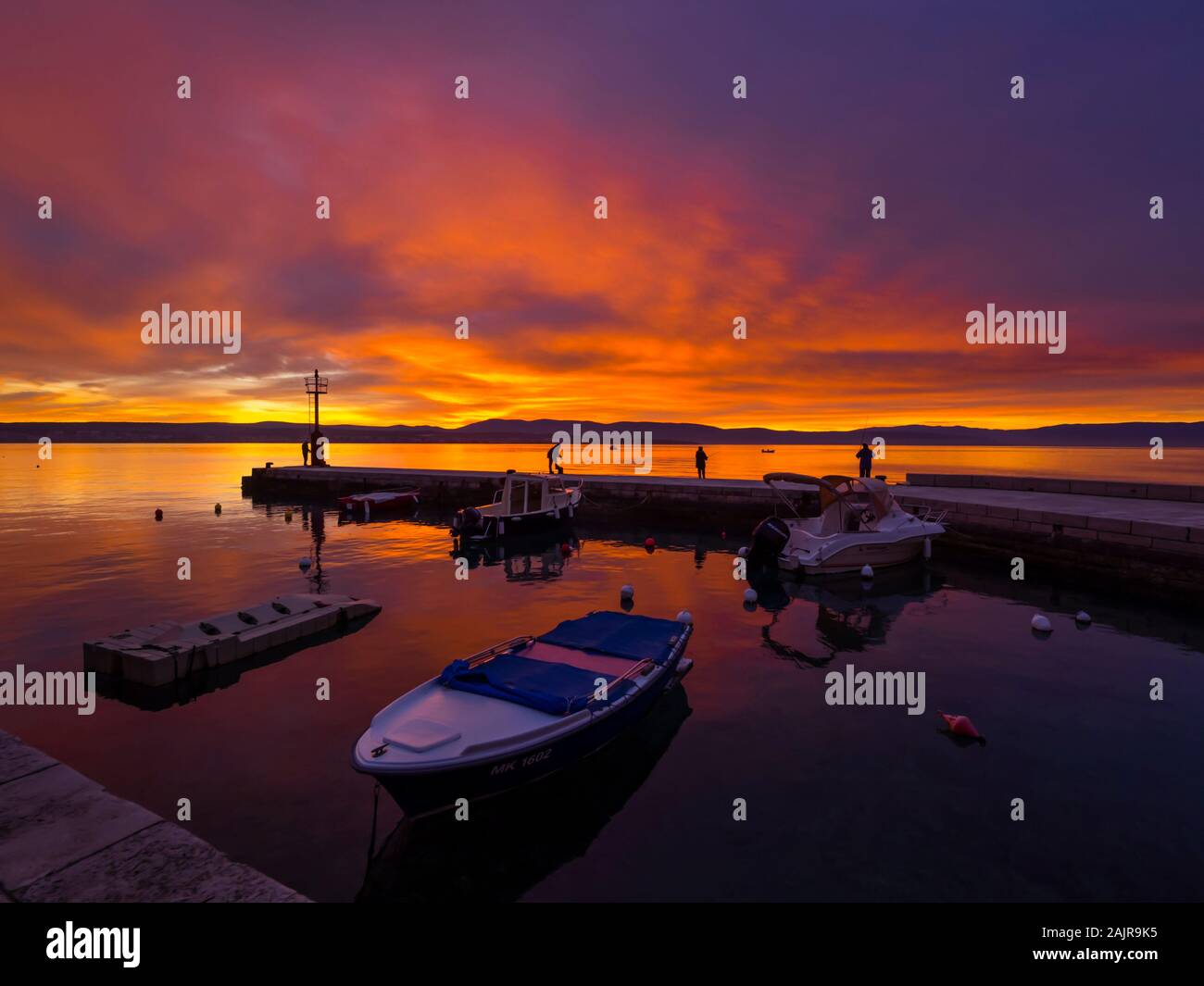 Fishermen before sunset scenery in small harbor in Malinska in Croatia glorious sky peaceful atmospheric seawall Ribarsko selo Haludovo Kvarner Stock Photo