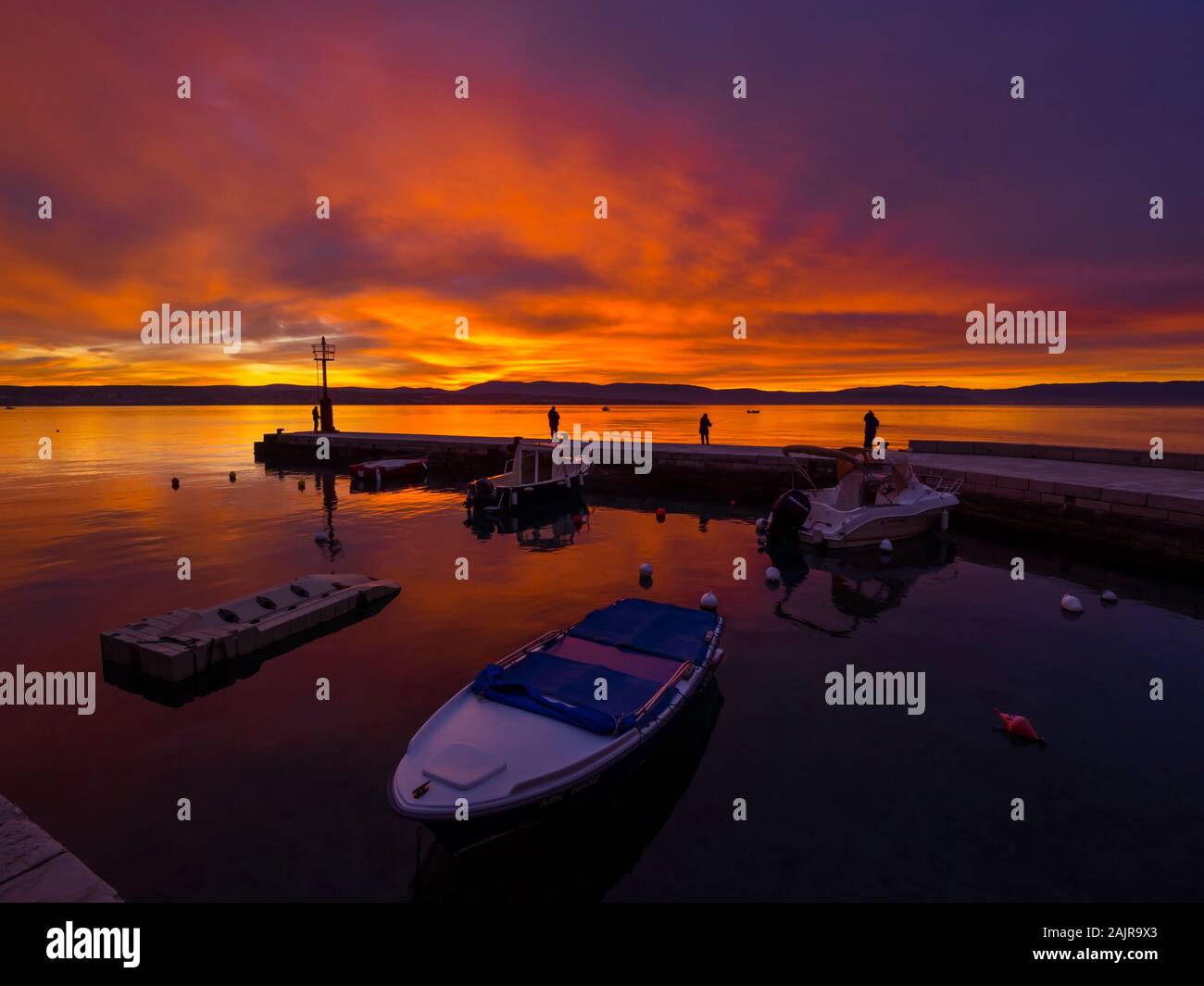 Fishermen before sunset scenery in small harbor in Malinska in Croatia glorious sky peaceful atmospheric seawall Ribarsko selo Haludovo Kvarner Stock Photo