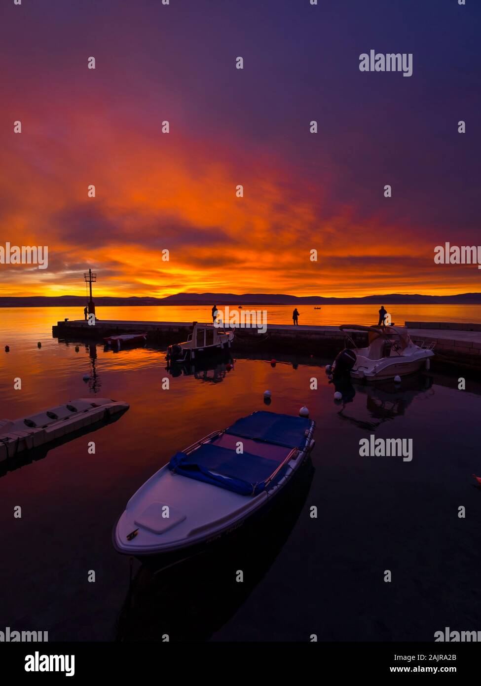 Fishermen before sunset scenery in small harbor in Malinska in Croatia glorious sky peaceful atmospheric seawall Ribarsko selo Haludovo Kvarner Stock Photo
