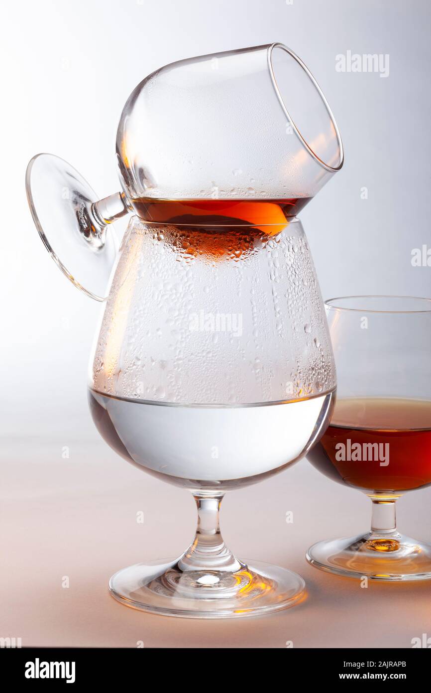 A snifter of brandy being warmed above a glass of hot water. The large