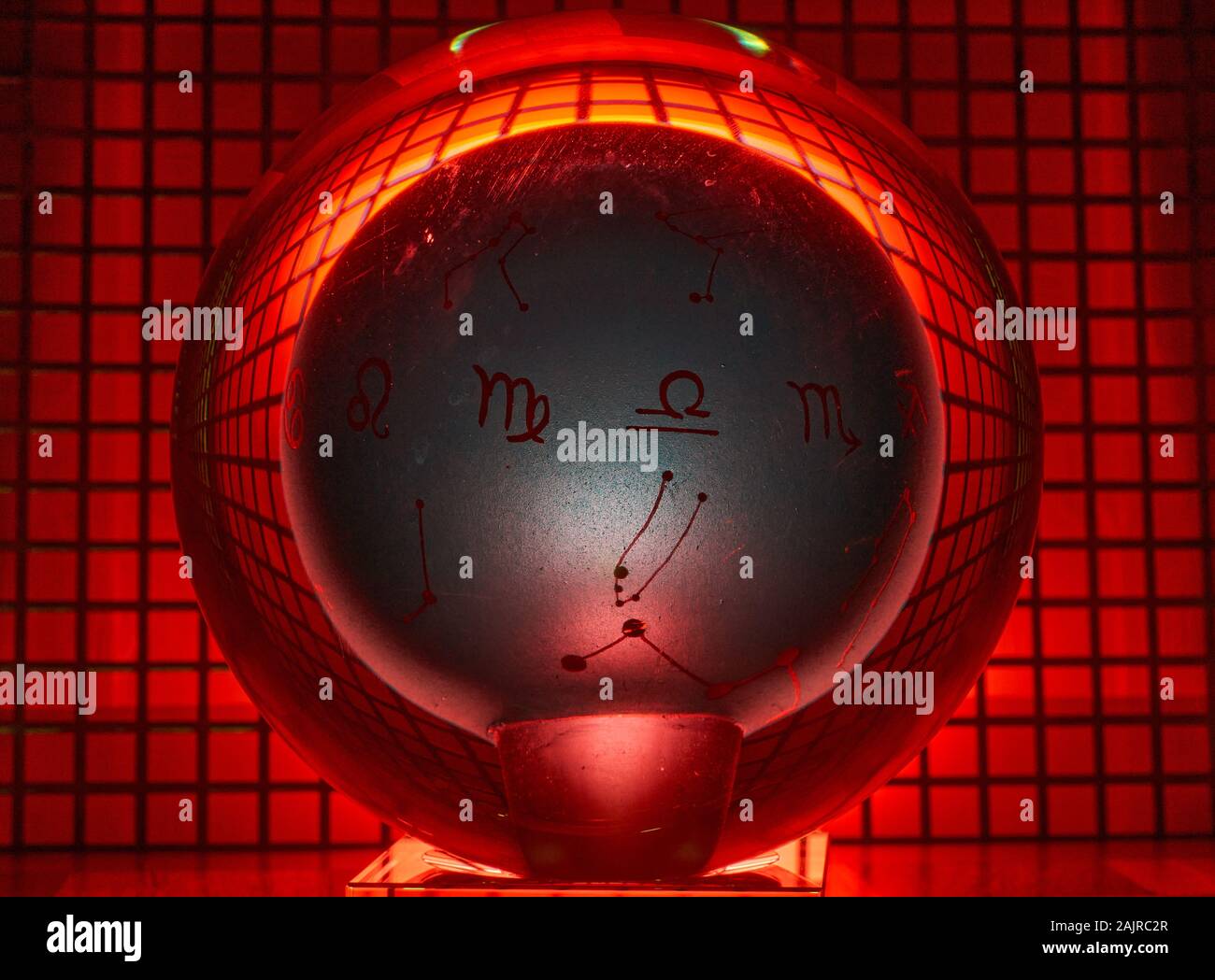Glass ball photographed on a perforated plate with red light. Stock Photo