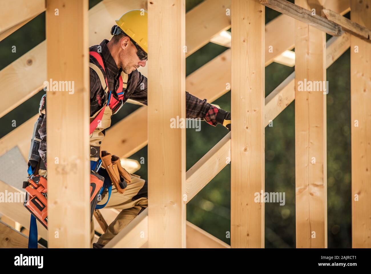 Wood Construction Job. Caucasian Contractor with Nail Gun in Hand Attaching Wood Beams. Industrial Theme. Stock Photo