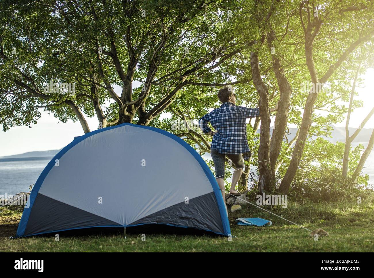 Woman in Her 60s on a Camping. Enjoying Sunny Morning in Front of Her Tent. Stock Photo