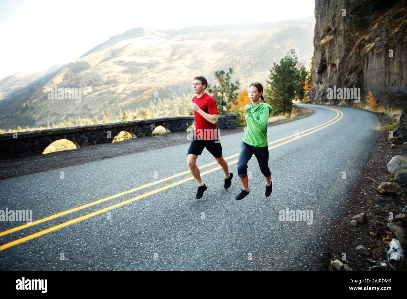 Two runners in their mid 20s running along scenic road in Rowena Stock Photo