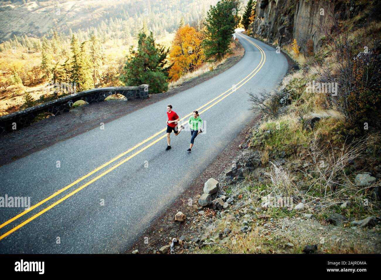 Two runners in their mid 20s running along scenic road in Rowena Stock Photo