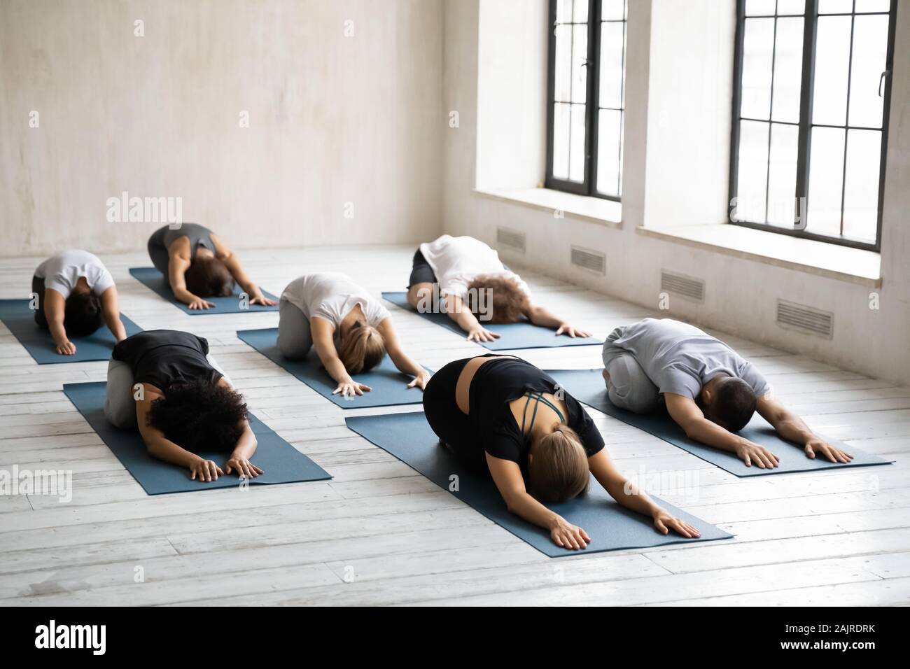 Diverse young people relaxing in Child pose, practicing yoga Stock Photo