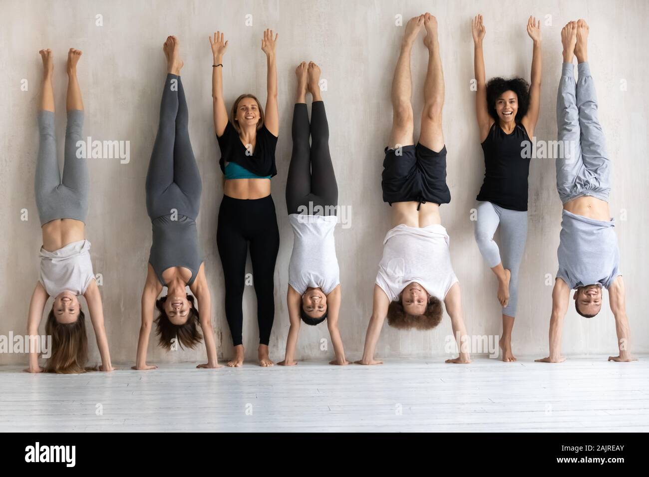 Happy diverse people doing handstand, fitness center staff portrait Stock Photo