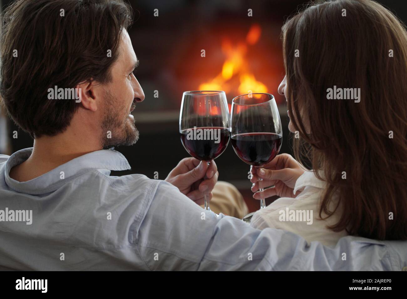 Romantic couple drinking wine at home near fireplace Stock Photo - Alamy
