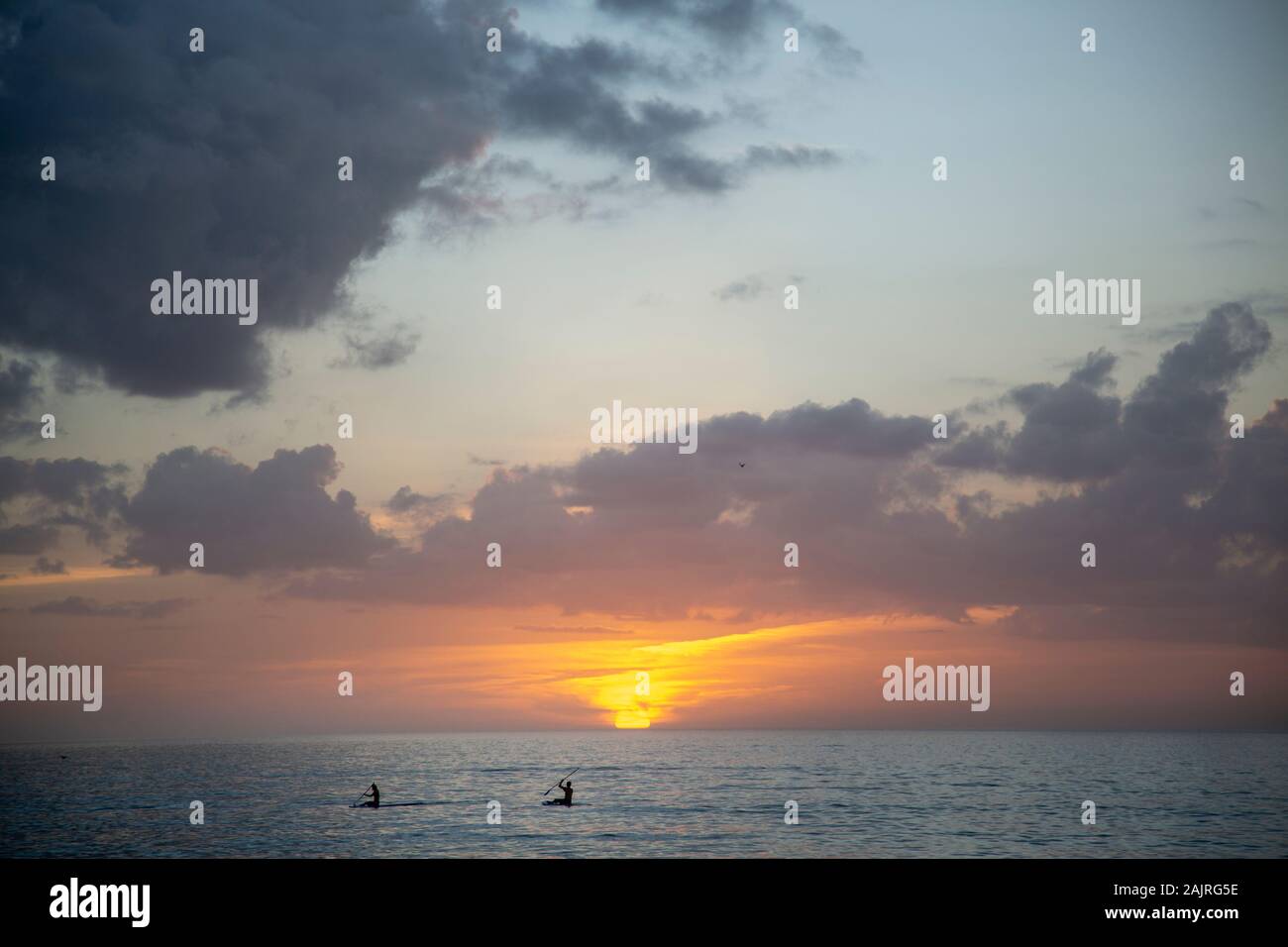 Two people kayaking on the ocean during sunset in Florida Stock Photo