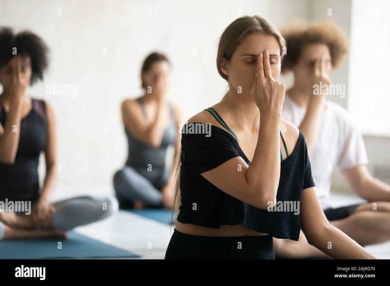 Woman doing Alternate Nostril Breathing exercise close up, practicing yoga Stock Photo