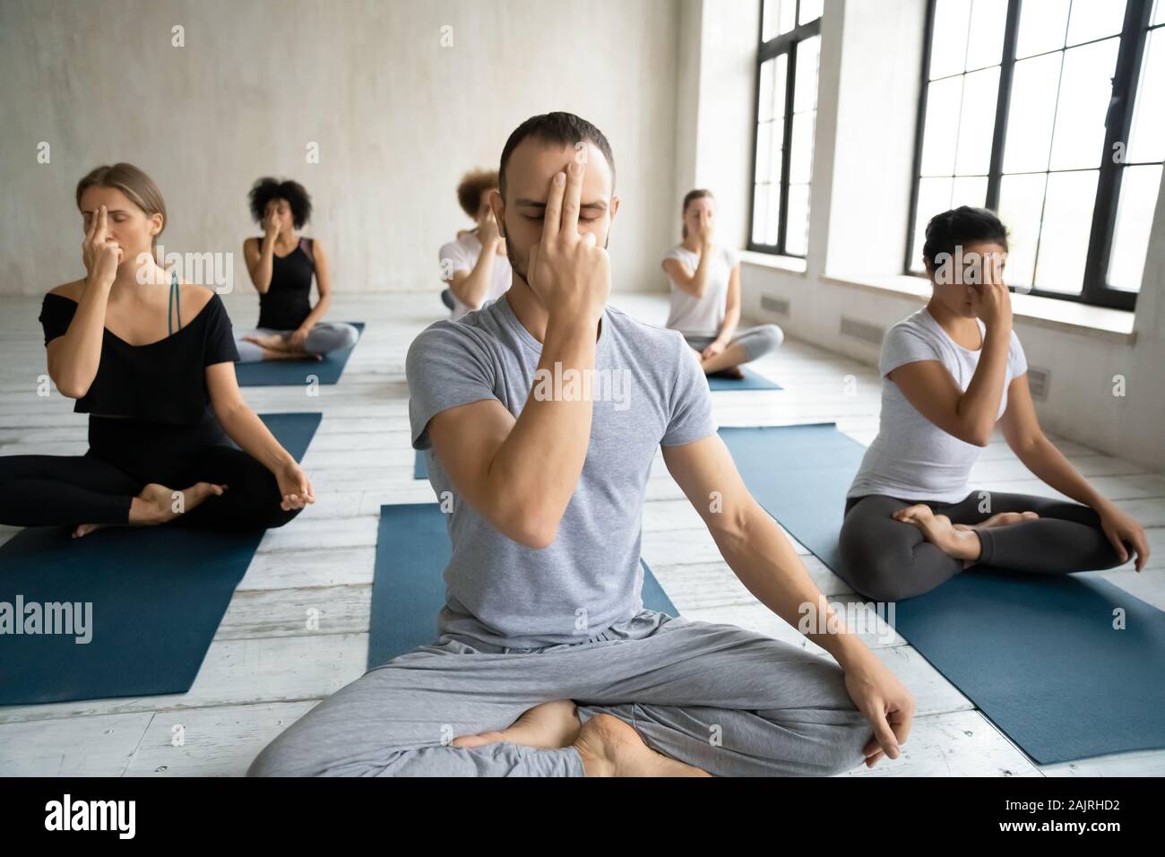Diverse people doing Alternate Nostril Breathing exercise, practicing yoga Stock Photo