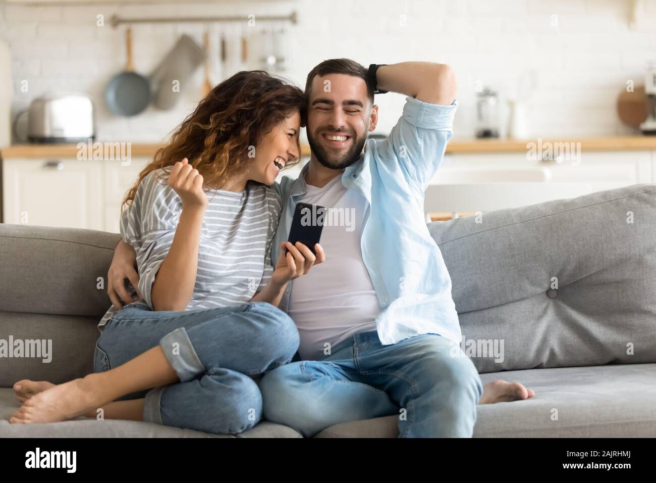 Cheerful married couple having fun using online amusing apps Stock Photo