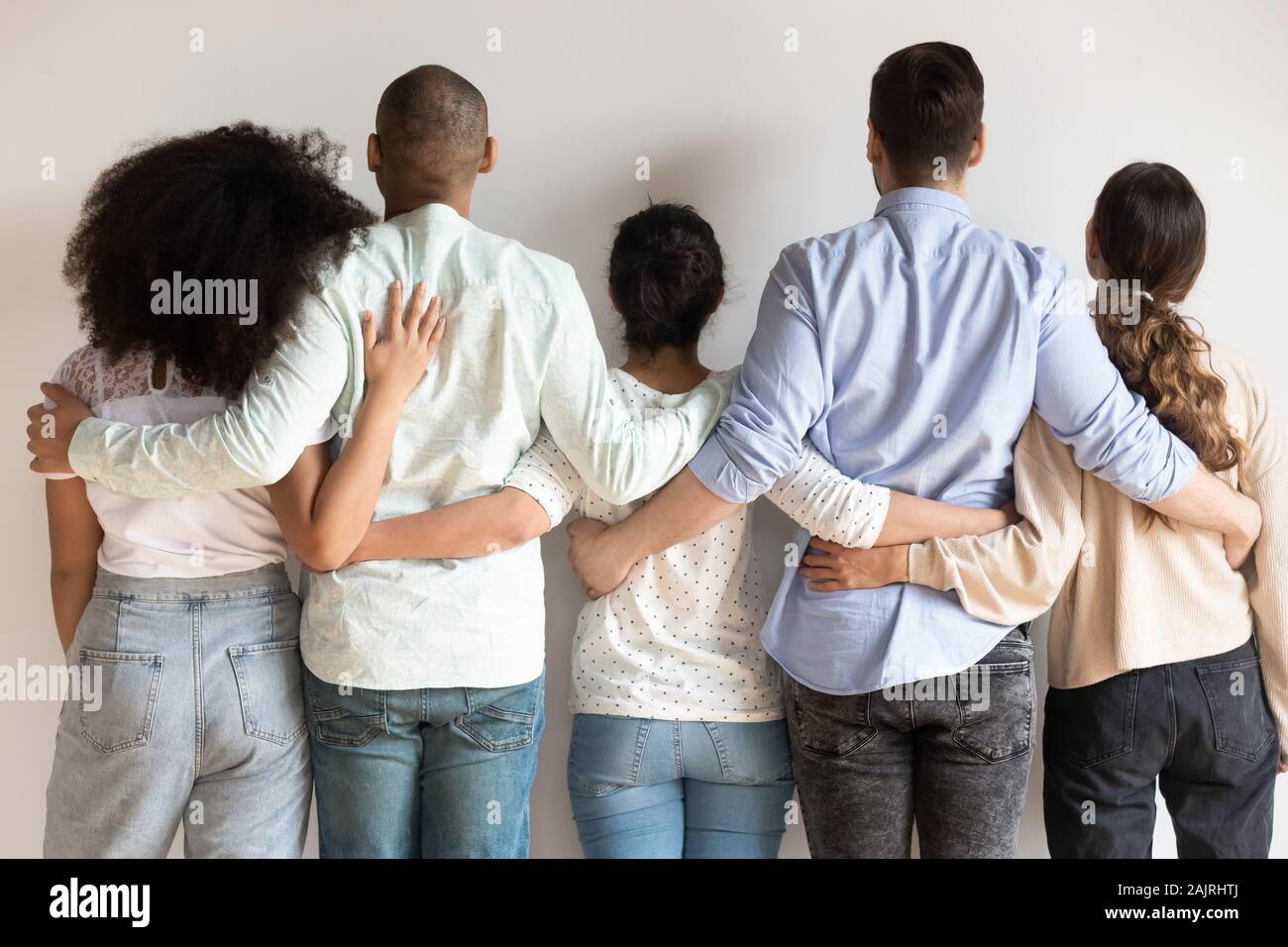 Back view of multiracial friends hug showing unity and support Stock Photo