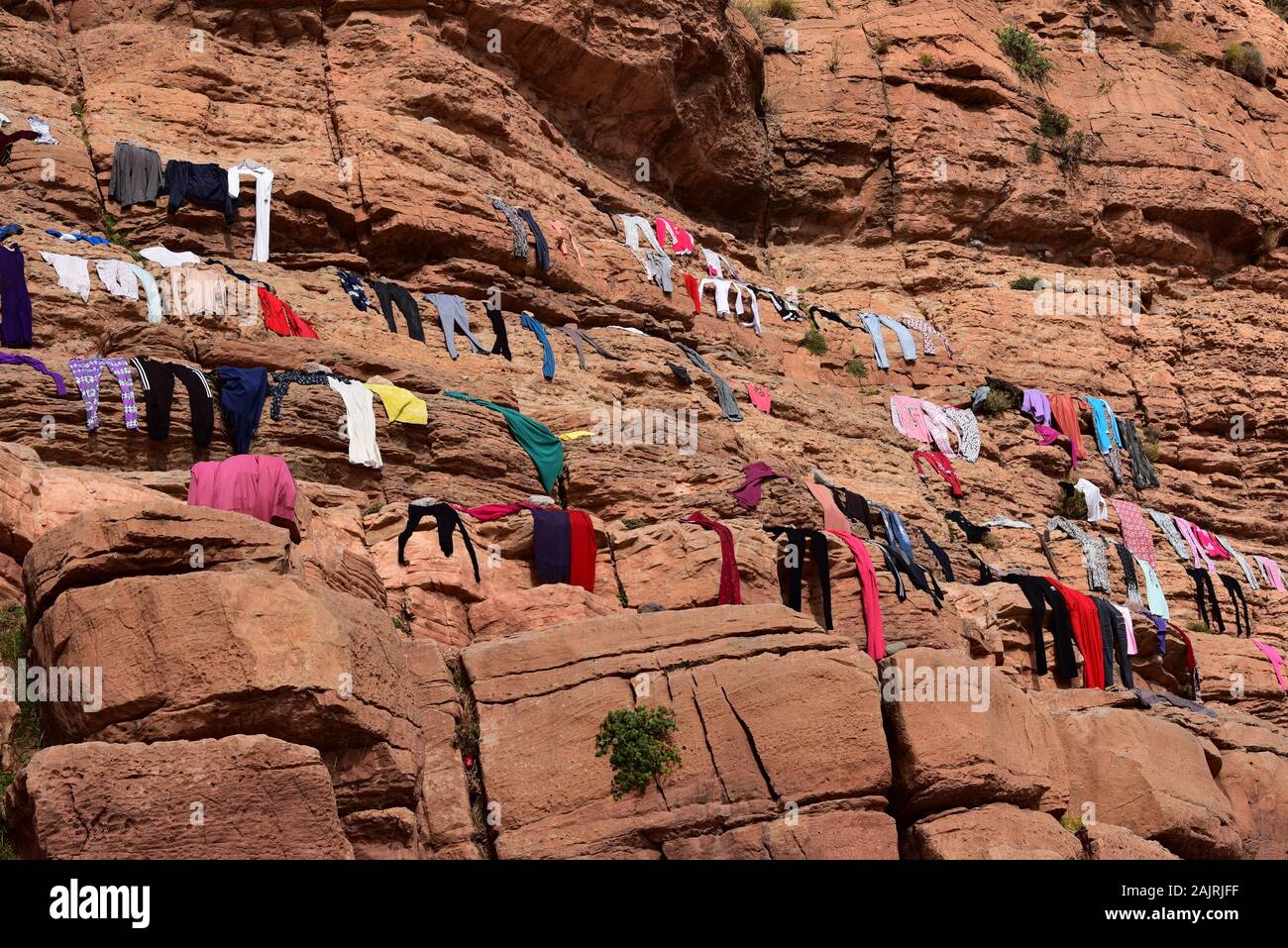 Village life - locals from the Moroccan village of Tighza lay out their laundry to dry on rocks under the midday sun, North Africa. Stock Photo