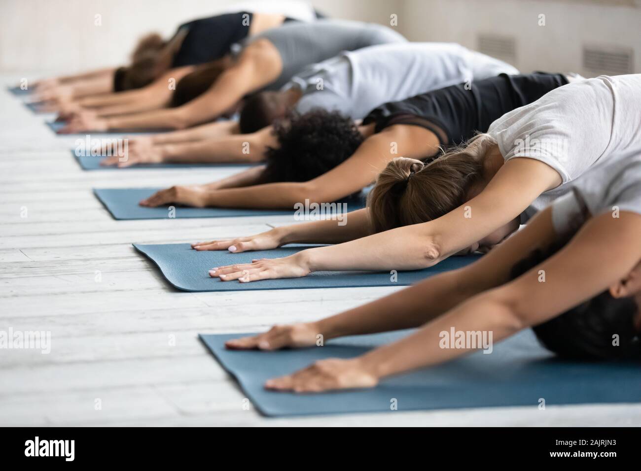 Diverse people stretching in Child pose in row, practicing yoga Stock Photo