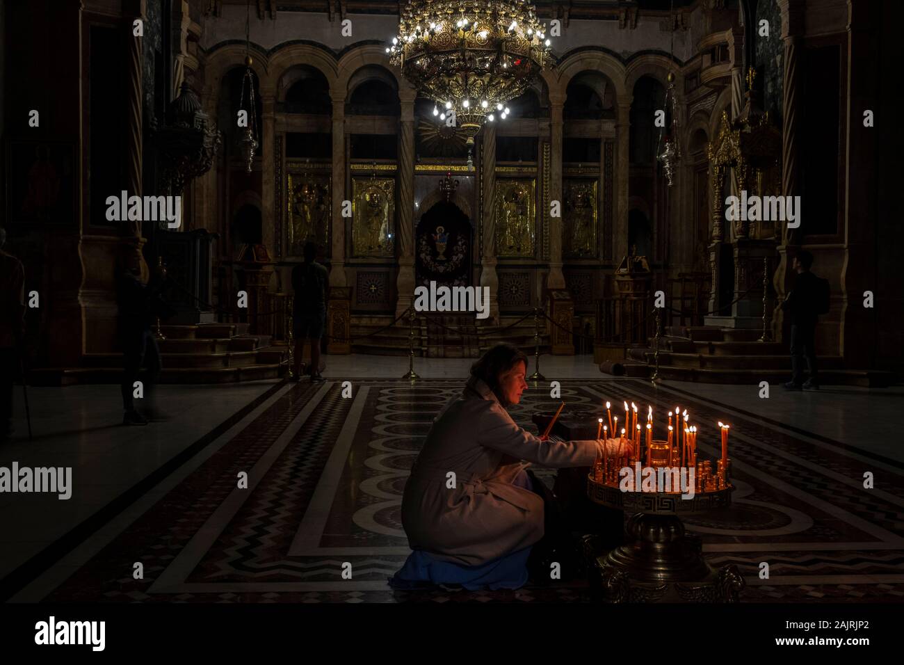 Woman lighting candles in Catholicon Altar Chapel in Holy Sepulchre in