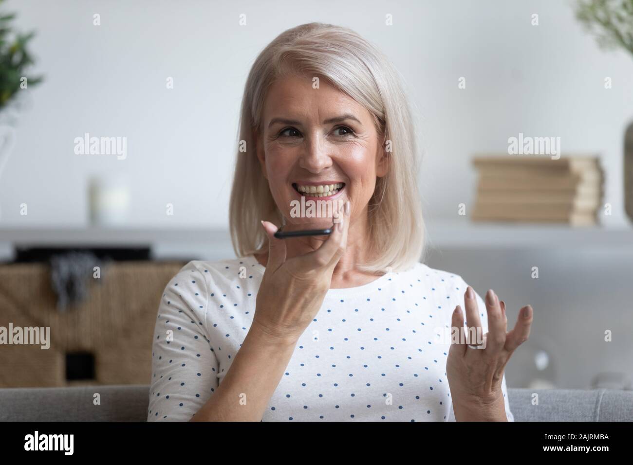 Modern elderly woman talk on cell using loudspeaker Stock Photo