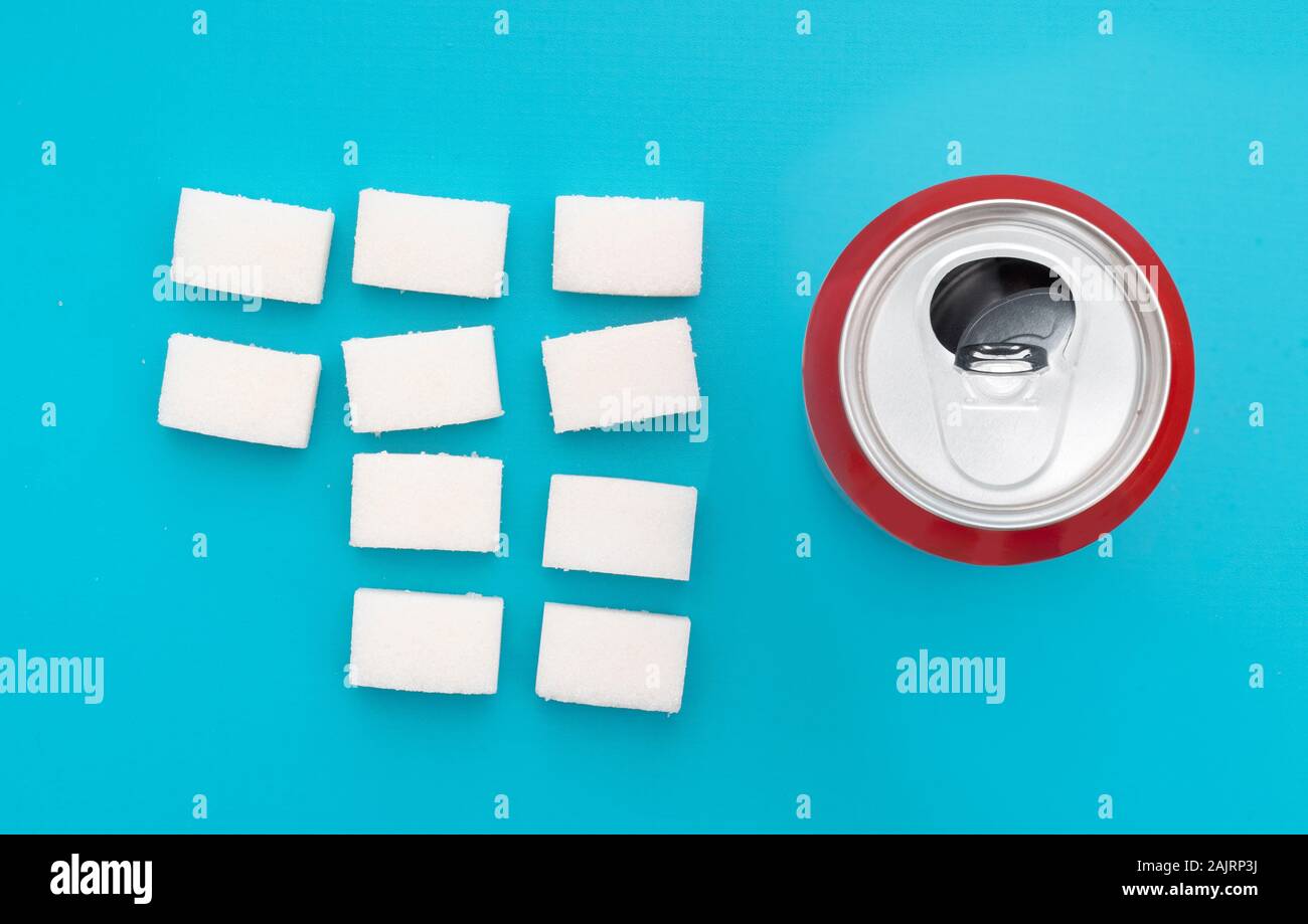 Unhealthy food concept - sugar in carbonated drinks. Sugar cubes and fizzy cola drink can. Flat lay, overhead view. Stock Photo