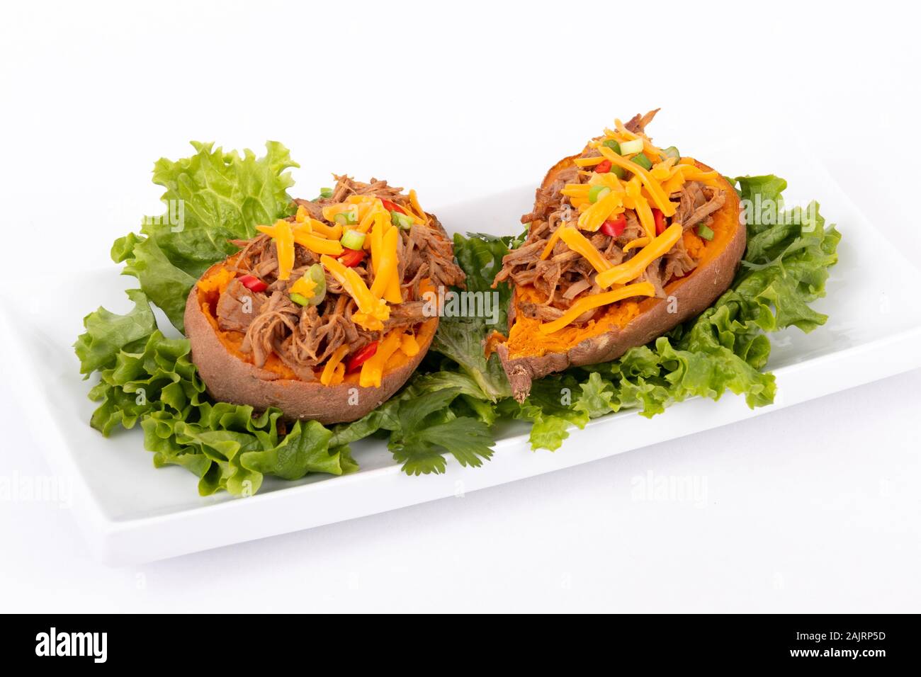delicious spicy pulled pork stuffed sweet potato skin yam dish over white background Stock Photo