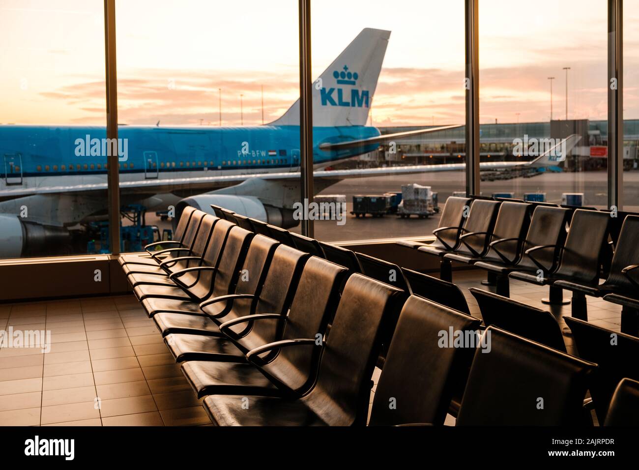 Amsterdam, Netherland - December, 2019: Empty seats in airport with KLM Airline airplane in background Stock Photo