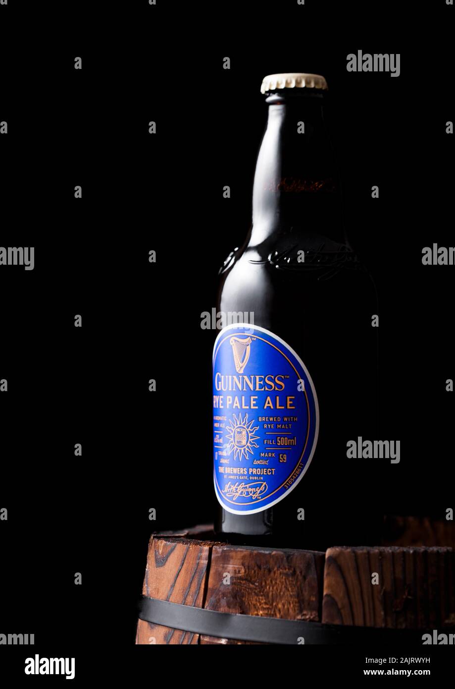 LONDON, UK - APRIL 27, 2018: Bottle of Guinness rye pale ale beer on top of old wooden barrel. Guinness beer has been produced since 1759 in Dublin, I Stock Photo
