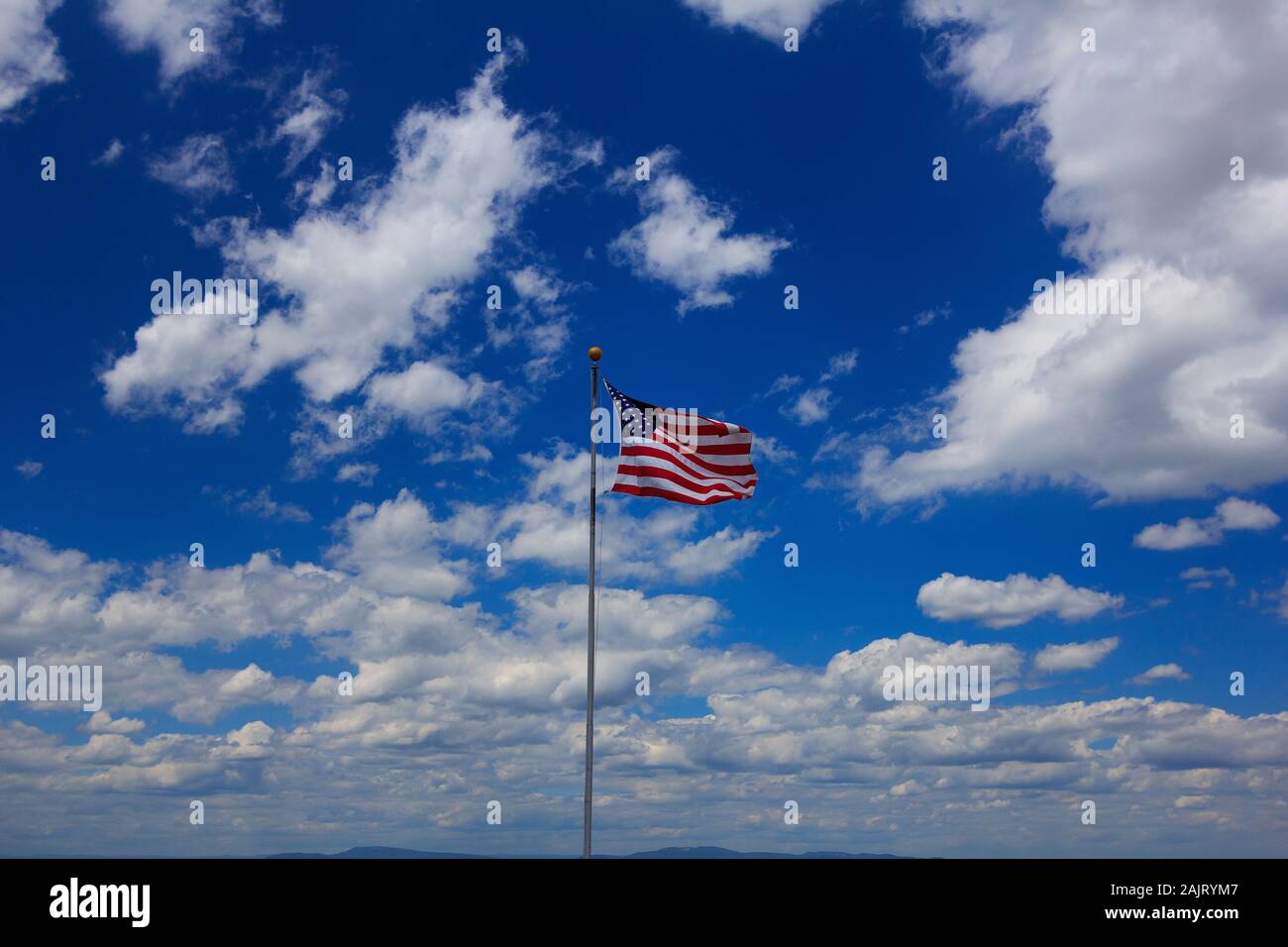 American Flag flying against blue sky and clouds with Blue Ridge Mountains in the background. Stock Photo